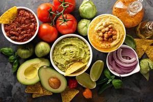 eigengemaakt hummus, salsa en guacamole met maïs chips foto