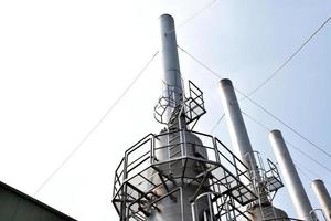 industrieel fabriek schoorstenen dat vrijlating giftig dampen in de atmosfeer foto