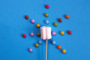 marshmallows samenstelling Aan houten spiesjes Aan blauw achtergrond. vlak leggen, vakantie concept. zonvormig snoepgoed foto