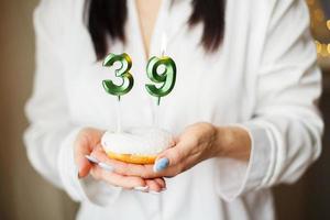 vrouw Holding een taart met de aantal 39 kaarsen foto