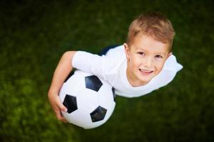 weinig jongen beoefenen voetbal buitenshuis foto