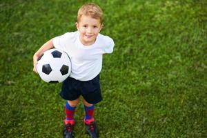 weinig jongen beoefenen voetbal buitenshuis foto