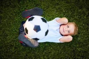 weinig jongen beoefenen voetbal buitenshuis foto