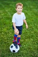 weinig jongen beoefenen voetbal buitenshuis foto