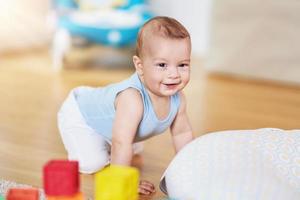 schattig glimlachen baby jongen kruipen Aan verdieping in leven kamer foto