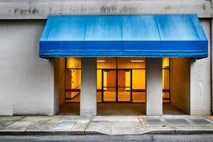 stad gebouw Ingang met blauw luifel foto