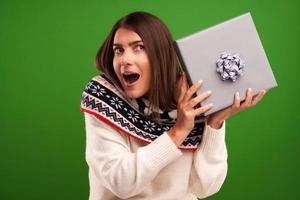 volwassen gelukkig vrouw met Kerstmis geschenk over- groen achtergrond foto