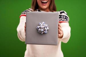 volwassen gelukkig vrouw met Kerstmis geschenk over- groen achtergrond foto