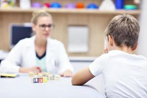 kind psycholoog werken met jong jongen in kantoor foto