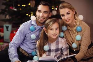 familie lezing verhaal boek samen onder Kerstmis boom foto