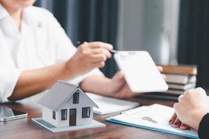 echt landgoed agenten aanbod contracten naar aankoop of huur residentieel. bedrijf persoon handen Holding huis model, klein gebouw rood huis. hypotheek eigendom verzekering in beweging huis en echt landgoed concept foto