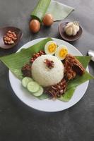 nasi lemak, is traditioneel Maleis gemaakt gekookt eieren, bonen, ansjovis, Chili saus, komkommer. van schotel geserveerd Aan een banaan blad foto