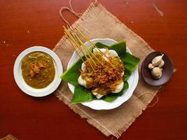 saté padang of saté padang is pittig rundvlees saté van padang, west sumatra. geserveerd met pittig kerrie saus en rijst- taart, lontong Aan banaan blad. geïsoleerd Aan wit achtergrond foto