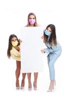 drie Dames in pastel pakken Holding aanplakbord poseren over- wit achtergrond foto