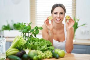 gezond volwassen vrouw met groen voedsel in de keuken foto