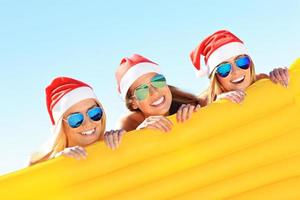 groep van meisjes in santa's hoeden hebben pret Aan de strand foto