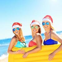 groep van meisjes in santa's hoeden hebben pret Aan de strand foto