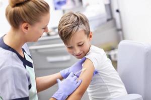 dapper weinig jongen ontvangen injectie of vaccin met een glimlach foto