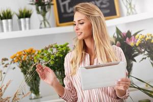 vrouw bloemist werken in bloem winkel met tablet foto