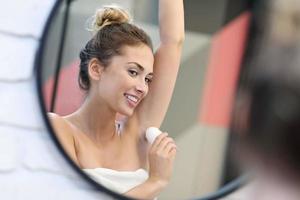 jong vrouw gebruik makend van deodorant in badkamer foto