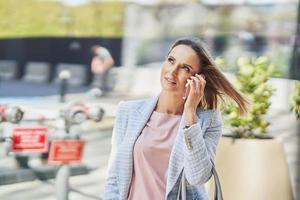 volwassen aantrekkelijk bedrijf vrouw met smartphone wandelen in de stad foto