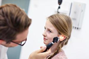 detailopname van mannetje dokter onderzoeken meisjes oor met een otoscoop foto