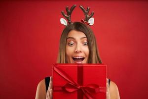 volwassen gelukkig vrouw met Kerstmis geschenk over- rood achtergrond foto