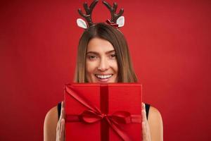 volwassen gelukkig vrouw met Kerstmis geschenk over- rood achtergrond foto