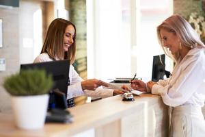 receptioniste en zakenvrouw Bij hotel voorkant bureau foto