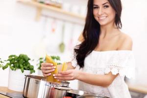 jong vrouw proberen naar bereiden pasta in keuken foto