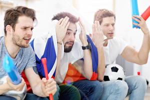 gelukkig mannetje vrienden juichen en aan het kijken sport- Aan TV foto