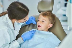 weinig jongen en vrouw tandarts in de tandartsen kantoor foto