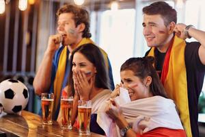 groep van vrienden aan het kijken voetbal in kroeg foto