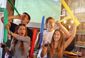 groep van vrienden aan het kijken voetbal in kroeg foto