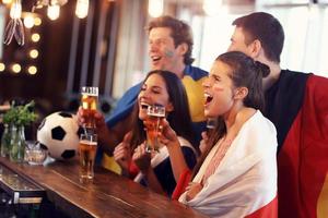 groep van vrienden aan het kijken voetbal in kroeg foto