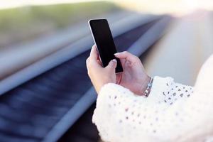 hand- Holding smartphone met spoorweg station achtergrond foto