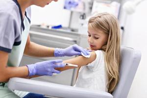 dapper weinig meisje ontvangen injectie of vaccin met een glimlach foto