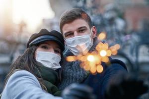 gelukkig paar vieren valentijnsdag dag in maskers gedurende covid-19 pandemisch foto