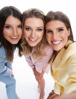 drie Dames in pastel pakken poseren over- wit achtergrond foto