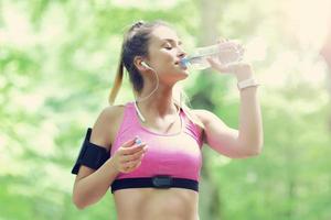 vrouw jogging in de Woud met fles van water foto
