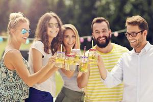 groep van jong mensen juichen en hebben pret buitenshuis met drankjes foto