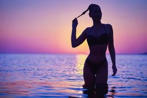 silhouet van sexy vrouw poseren Bij zonsopkomst Bij de strand foto