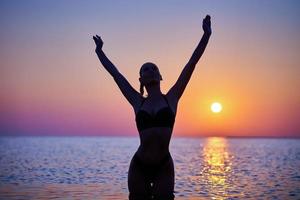 silhouet van sexy vrouw poseren Bij zonsopkomst Bij de strand foto