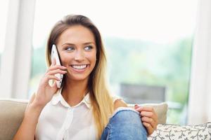 vrouw Aan bankstel met smartphone in leven kamer foto