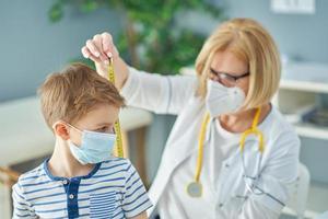 kinderarts dokter onderzoeken weinig kinderen in kliniek meten plakband foto