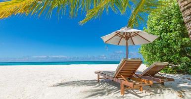 rustig strand tafereel. panoramisch tropisch strand landschap voor achtergrond of behang, twee lounge stoelen met paraplu. ontwerp van zomer vakantie vakantie concept foto