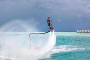 water extreem sport, zomer zee en tropisch weer met buitenshuis actief mensen genieten van water sport. vlieg bord, surfing in oceaan, pret en zomer recreatief werkzaamheid. flyboarden en zeerijden foto