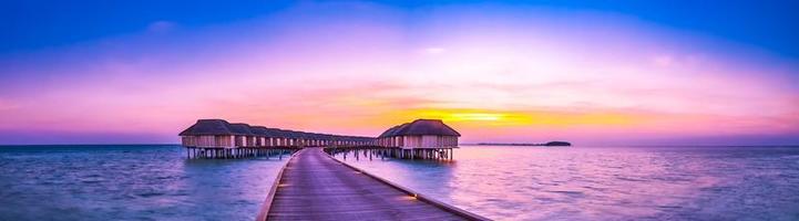 verbazingwekkend zonsondergang panorama Bij Maldiven. luxe toevlucht villa's zeegezicht met zacht LED lichten onder kleurrijk lucht. Maldiven zonsondergang zeegezicht visie. horizon met zee en kleurrijk lucht. geweldig zonsondergang landschap foto
