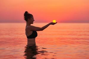 jong vrouw zwemmen in de zee Aan zonsopkomst foto