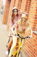 twee meisje vrienden rijden tandem fiets foto